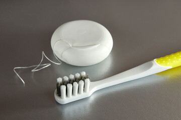 Dental floss and a toothbrush on a gray background. Dental care.