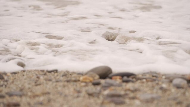 Detalle de la orilla de una playa pedregosa a c&aacute;mara lenta