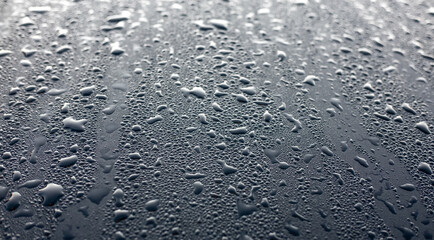 Dew drops on the black hood of a parked car. Background