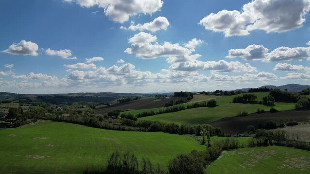 Verdi colline con cielo nuvoloso, con una piccola strada che li costeggia