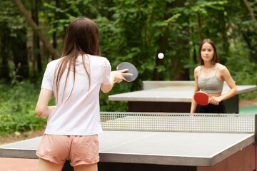table tennis outdoor, teenager playing ping pong with table tennis rackets in the summer in the...