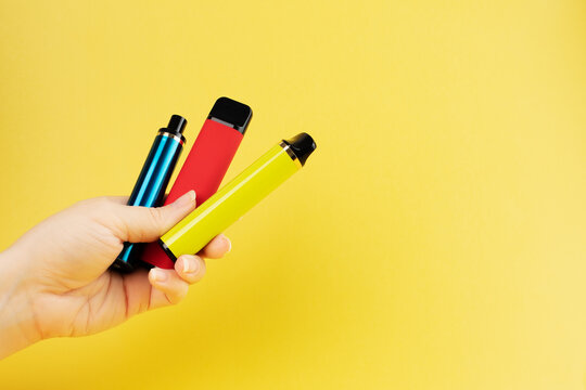 different electronic cigarettes in the smoker's hand on a yellow background
