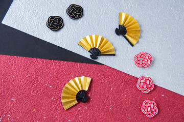 日本の正月イメージ　金色の扇と紅白や黒の水引と3色の和紙（銀色とえんじと黒の背景）