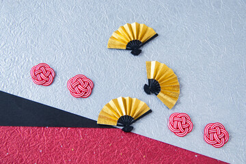 日本の正月イメージ　金色の扇と紅白の水引と3色の和紙（銀色とえんじと黒の背景）