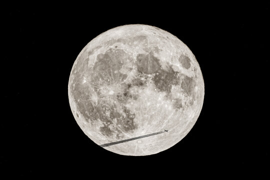 Passenger plane and black chemtrails transiting in front of the Super Moon