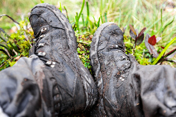Fototapeta na wymiar Dirty, muddy and worn out hiking boots of tourist in Baliem Valley, after a long trek in the highlands of West Papua, Indonesia
