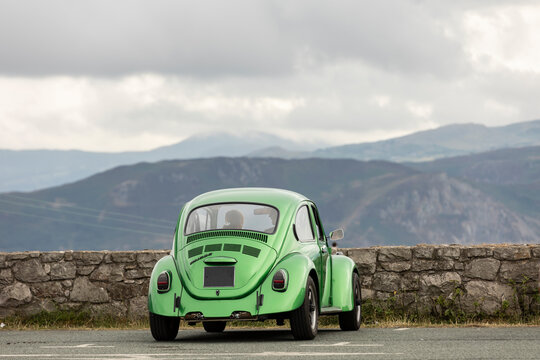 Llandudno north Wales united kingdom 01 August 2022 lime green vw beetle car parked overlooking welsh mountains with male and female passengers romantic concept, copy space