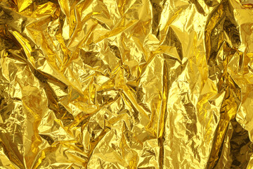 Gold and bronze glitter foil crumpled paper. Abstract glow shine texture copy space background.