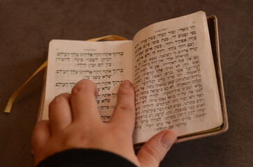 open pretty Jewish item prayer book siddur with hebrew letters with woman pointing at the words and praying