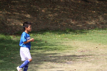 芝生でサッカーの練習をする子供