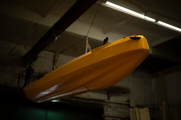 Boat in garage. Boat hangs from ceiling. Sports equipment. Water transport. Vehicle.