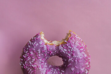 Donut With violet Icing And Colored Sprinkles on violet background. Tasty delicious fat high...