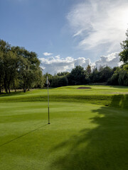 Flag and the hole at golf club blue sky summers day with some clouds