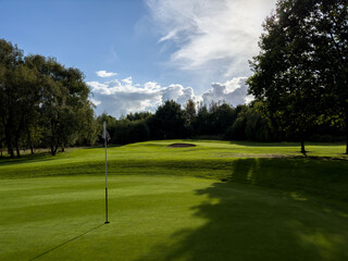 Flag and the hole at golf club blue sky summers day with some clouds