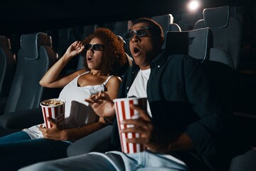 A couple in love, friends watching a movie with popcorn in the cinema.