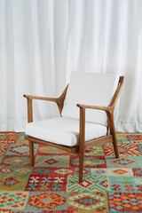 Danish Modern Armchair with white cushions on a colorful hand-knotted rug before luxurious white curtains