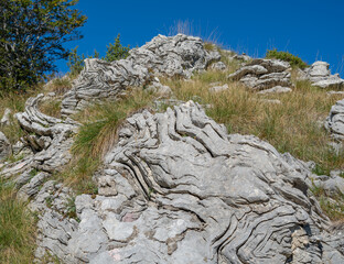 A strange undulating rock configuration on a mountain surrounded by grass
