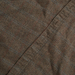 Plaid fabric pattern detail. Warm gray cloth texture with seam. Closeup of vintage clothing.