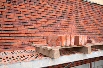 a new House is being built, the beginning of brickwork with red bricks, building