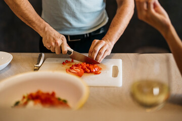 Caucasian man cuts tomato for a salad on a chopping board in a kitchen
