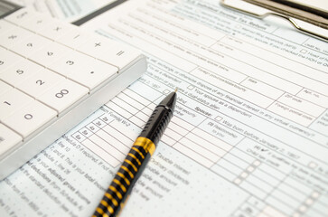 Naklejka na ściany i meble Tax form with pen and calculator on white background