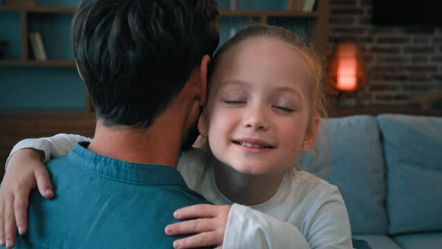 Loving cute daughter hugging adorable daddy happy young caucasian family single father embracing little child girl at home on Father's day parental love tenderness emotions relaxing together on sofa
