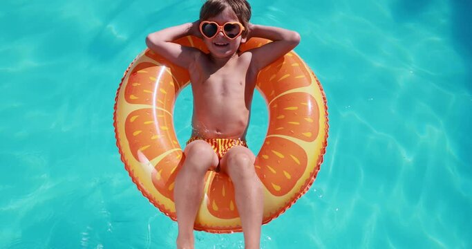 Happy child having fun on summer vacation. Kid playing in swimming pool. Active healthy lifestyle concept. Slow motion