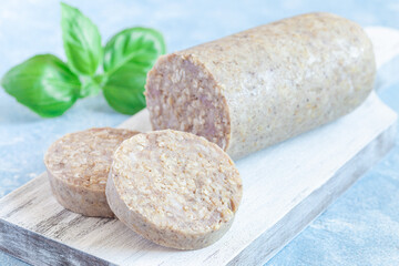 Traditional Irish white or oatmeal pudding sausage slices on a wooden board, horizontal