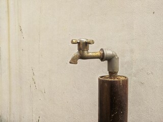 old rusty faucet against a wall in a courtyard