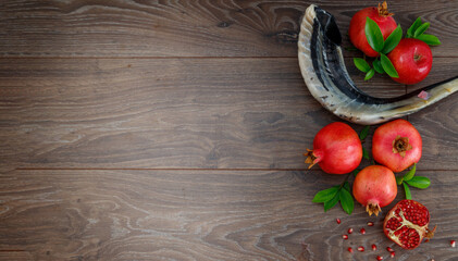 Pomegranates, red apples, shofar (horn) on a wooden table, the concept of the Jewish new year - Rosh Hashanah. Top view