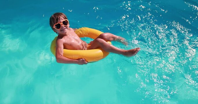 Happy child having fun on summer vacation. Kid playing in swimming pool. Active healthy lifestyle concept. Slow motion