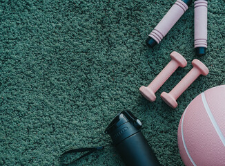 Set of sport accessories on green background. Fitness equipment, dumbbells, skipping rope. Sport gear, close up