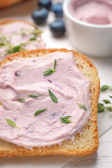 Tasty sandwiches with cream cheese and thyme on white wooden table, closeup