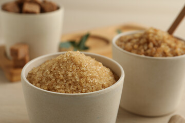 Brown sugar in bowl on wooden table, closeup