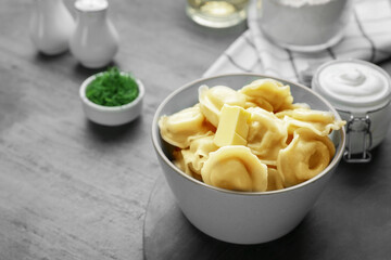 Tasty dumplings in bowl served on grey table, space for text