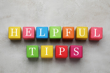 Text Helpful Tips made of colorful cubes with letters on grey table, top view