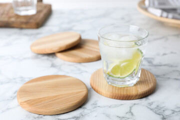 Fototapeta na wymiar Glass of lemonade and stylish cup coasters on marble table, space for text