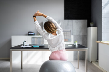 Employee Exercising On Ball In Office