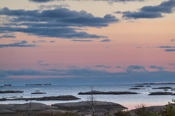 Fototapeta na wymiar Looking out on Georgian Bay at sundown, over low humps of exposed granite rock to a horizon of blue clouds and a pink tinged sky. Shot on Whitefish Bay in September.