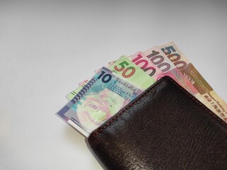 10.50.100.500 Hong Kong dollars currency flanked by brown wallet isolated on white background.