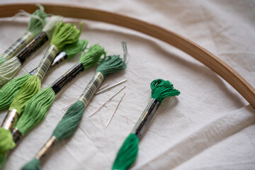 madejas de hilo de algodón para bordar de diferentes colores sobre tela, aro de madera con agujas...