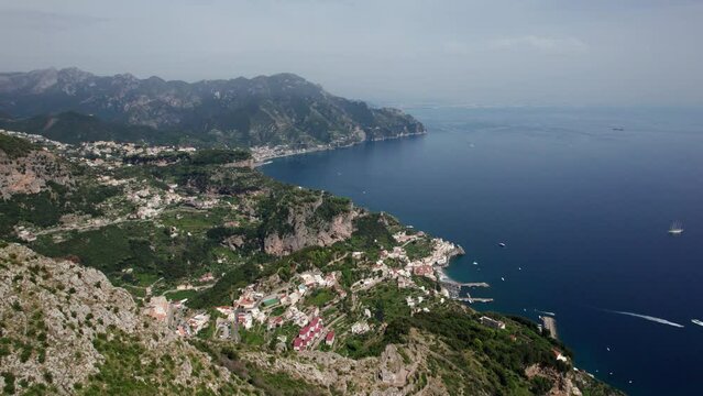Aerial orbit shot of Amalfi and Ravello on the Amalfi Coast, Italy, with mountains in foreground, and Mediterranean seascape in background. Beautiful Italian beaches and coastline drone shot in 5.4K