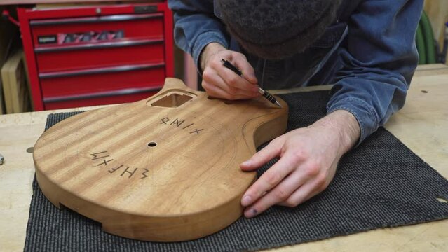 Professional luthier drawing curve for carving on the back of guitar body