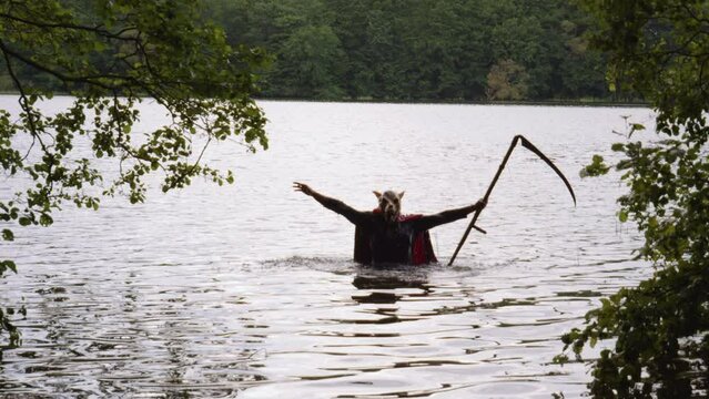 Static view of a man with dog head and scythe rising from the waters. Horror