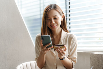 Young pretty asian female using credit card to do online product shopping on her mobile, cashless...