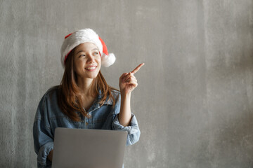 Pretty asian woman wearing santa hat with laptop.