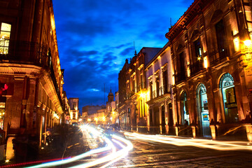 Fototapeta na wymiar dark streets with golden lights and dusk sky blue color, colonial buildings in zacatecas at night 