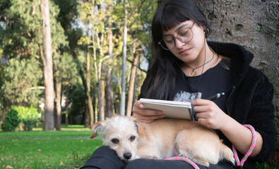 Universitaria estudiando al aire libre en compañía de su perro