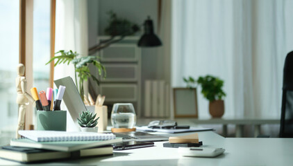 Comfortable home office with laptop computer, houseplant and supplies.