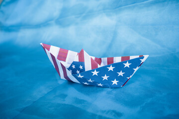 Paper boat with American flag on blue background.  Columbus day concept.